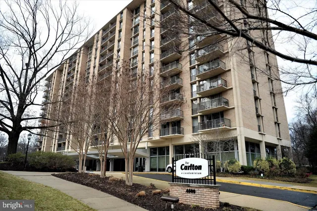 a front view of a building with lot of cars and trees