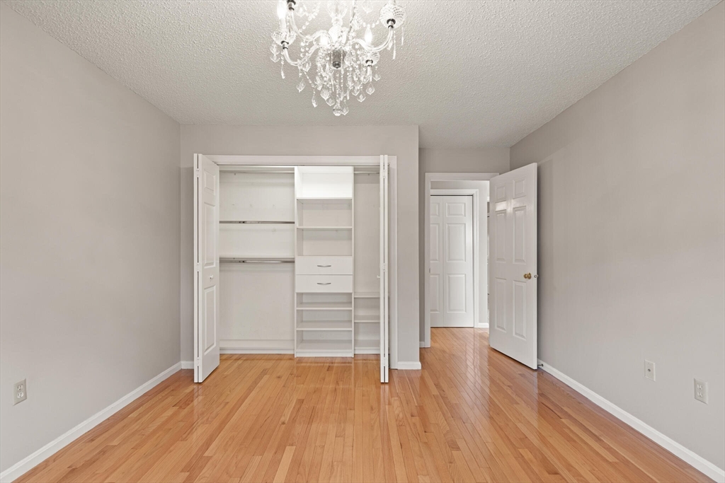 6 Countryside Lane, Unit 1303 Salem, MA 01970 - Photo 14 of 26 wooden floor in an empty room with a chandelier