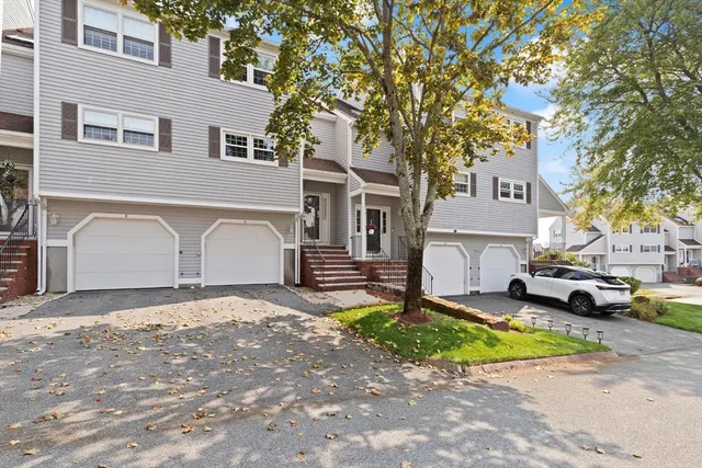 a view of a white house in front of a yard with parked cars