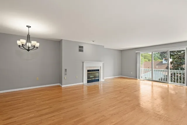 a view of empty room with wooden floor and fireplace