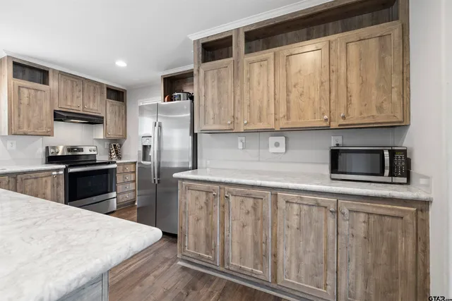 a kitchen with kitchen island granite countertop wooden cabinets a refrigerator and a sink