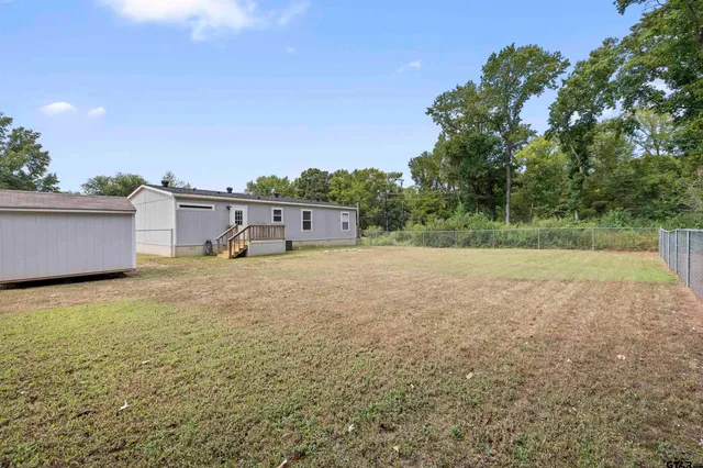 a view of a big yard with plants and a bench in the background