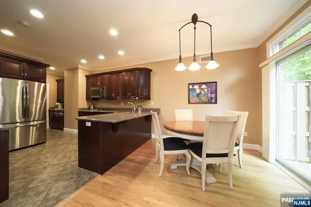 a kitchen with stainless steel appliances a dining table chairs and refrigerator