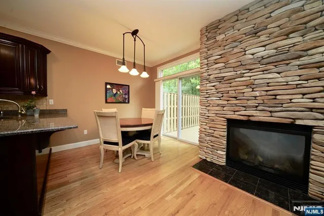 a dining room with a wooden floor a fireplace a rug and a chandelier