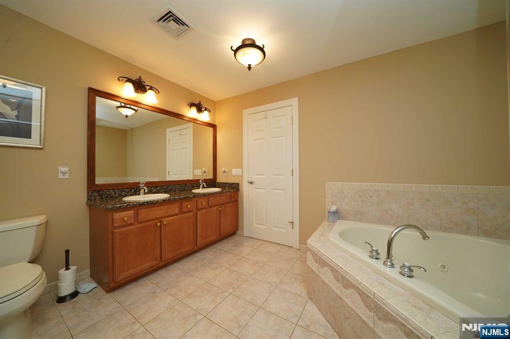 1 Candlewood Drive, Unit 1 Old Tappan, NJ 07675 - Photo 19 of 27 a bathroom with a granite countertop sink a toilet and bathtub