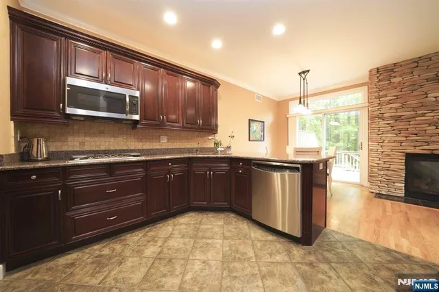 a kitchen with stainless steel appliances granite countertop a stove a sink and a microwave