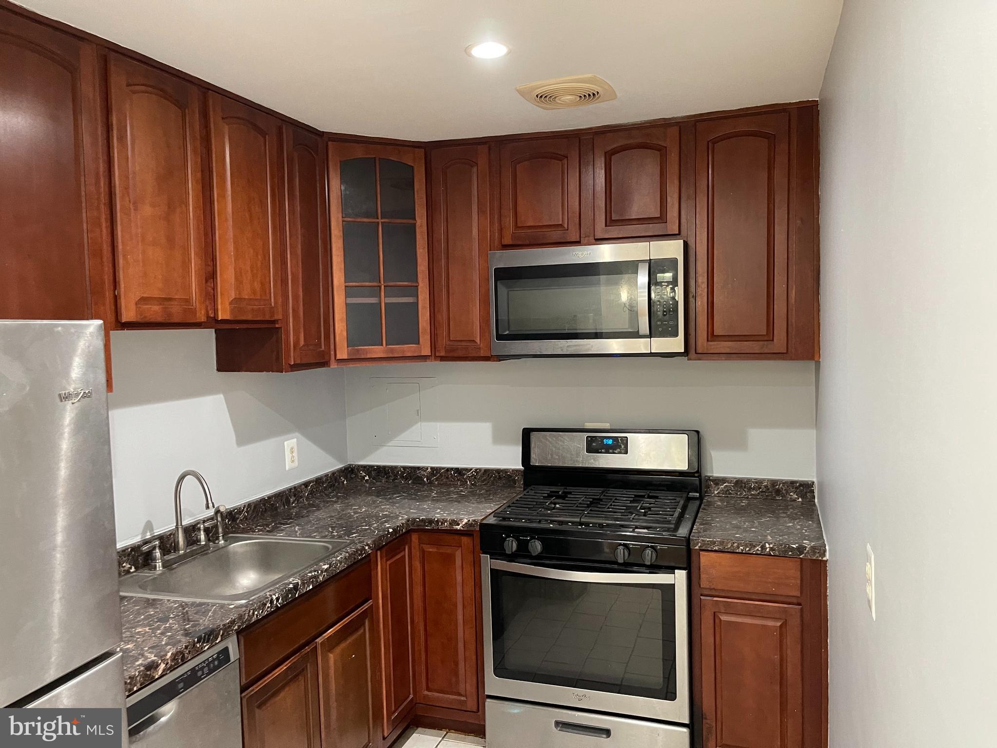 5106 F Street Southeast, Unit 8 Washington, DC 20019 - Photo 6 of 39 a kitchen with granite countertop a stove top oven microwave and cabinets