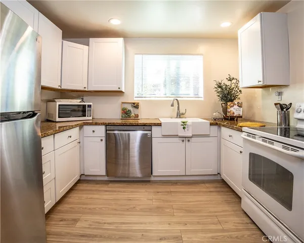 a kitchen with a sink white cabinets and white appliances