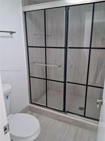 a white toilet sitting next to a shower