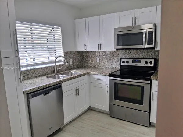 a kitchen with stainless steel appliances granite countertop a sink a stove a microwave and wooden cabinets