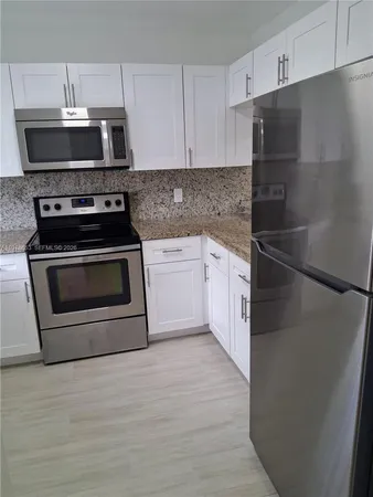 a kitchen with stainless steel appliances granite countertop a stove a refrigerator and a microwave