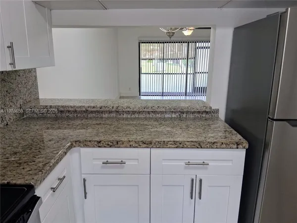 a kitchen with granite countertop cabinets and white stainless steel appliances