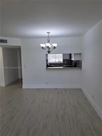 an empty room with wooden floor a sink and chandelier fan