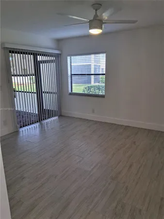 an empty room with wooden floor fan and windows