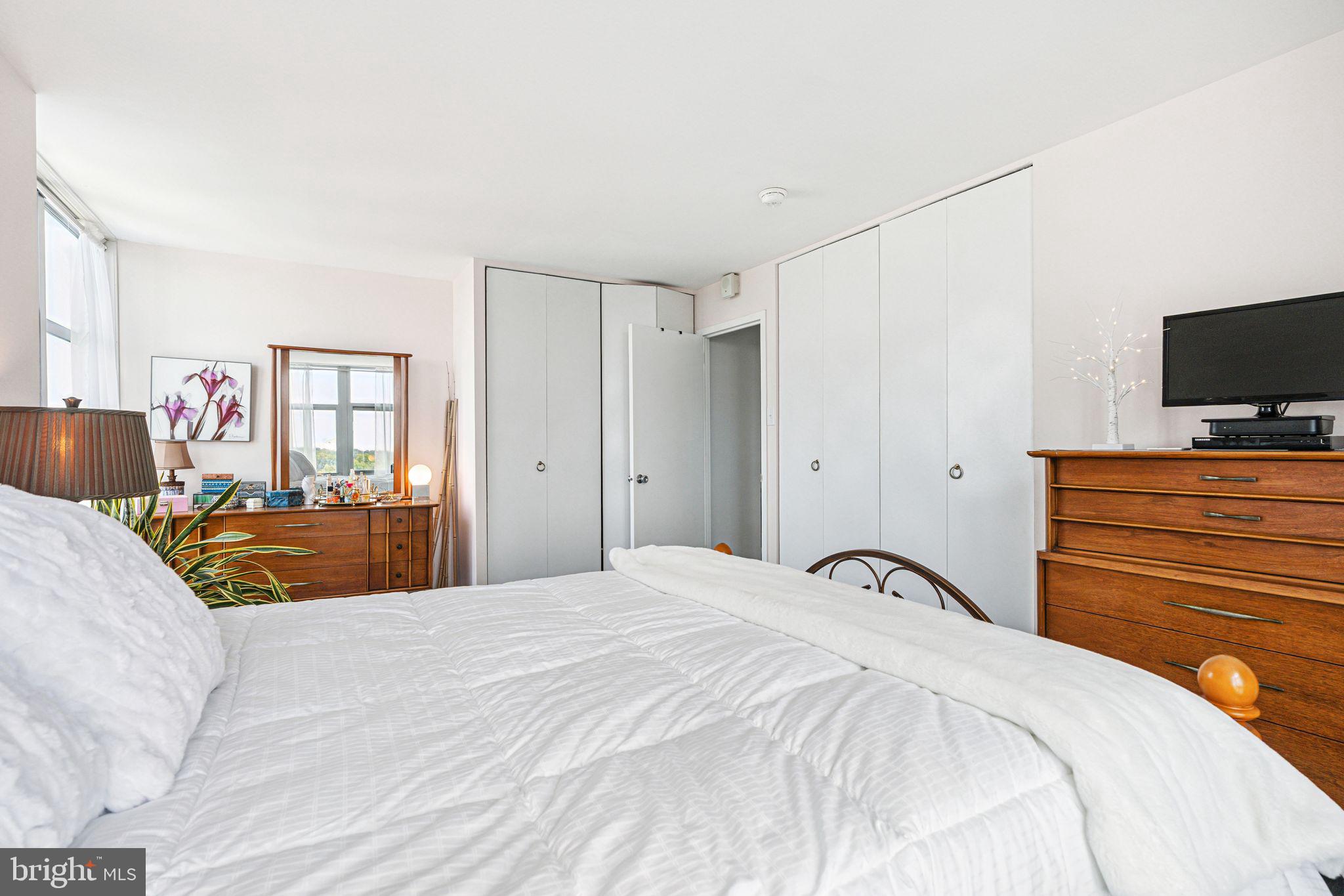 3600 Conshohocken Avenue, Unit 1712 Philadelphia, PA 19131 - Photo 19 of 27 a bedroom with a bed and dresser with mirror