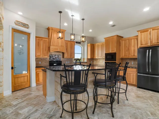a kitchen with stainless steel appliances kitchen island granite top and refrigerator