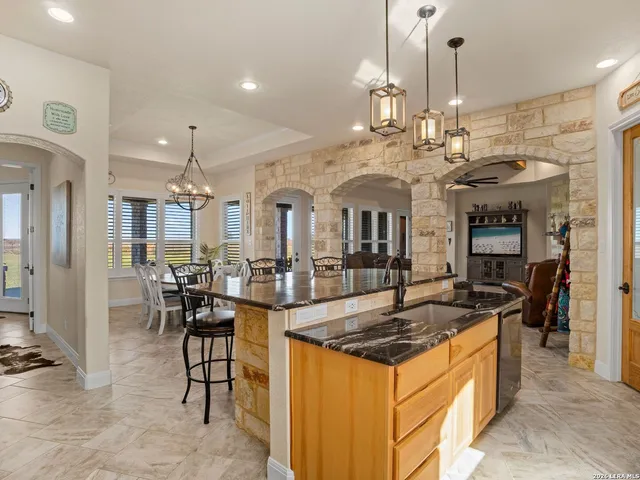 a kitchen with stainless steel appliances granite countertop a sink a stove and a wooden floors