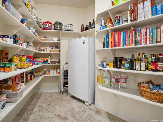 a storage room with stainless steel appliances lots of white furniture