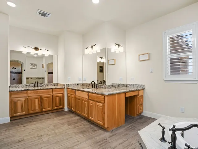 a bathroom with a double vanity sink a toilet a mirror and shower