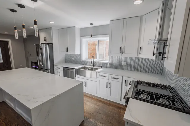 a kitchen with stainless steel appliances a sink a stove a refrigerator and cabinets