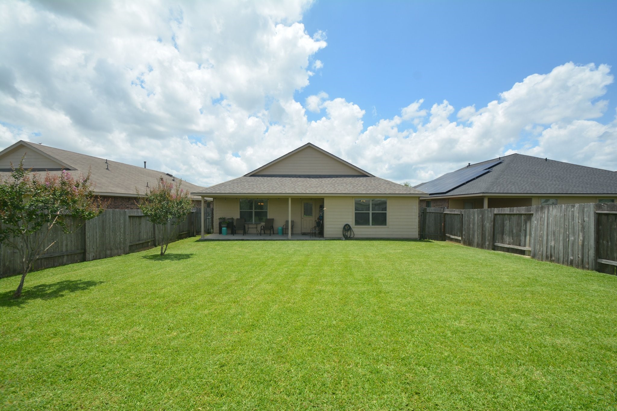 23318 Dukes Run Drive Spring, TX 77373 - Photo 38 of 41 Spacious backyard with a well-maintained lawn, bordered by wooden fencing for privacy. The house features a covered patio, ideal for outdoor relaxation.