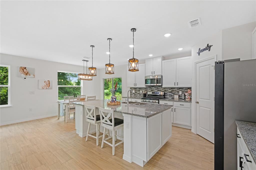 1137 Bradford Rdg Drive Leesburg, FL 34748 - Photo 3 of 37 a kitchen with stainless steel appliances kitchen island granite countertop a stove a refrigerator a oven a sink with a dining table and chairs