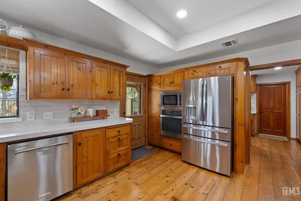 a kitchen with stainless steel appliances granite countertop a refrigerator microwave and wooden floor