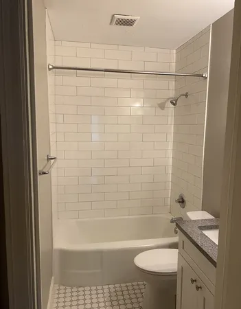 a bathroom with a granite countertop bathtub shower sink vanity and toilet