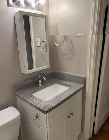 a bathroom with a granite countertop sink and a mirror
