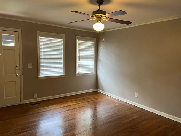 a view of a room with wooden floor fan and windows