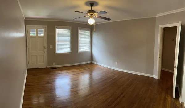 an empty room with wooden floor and windows