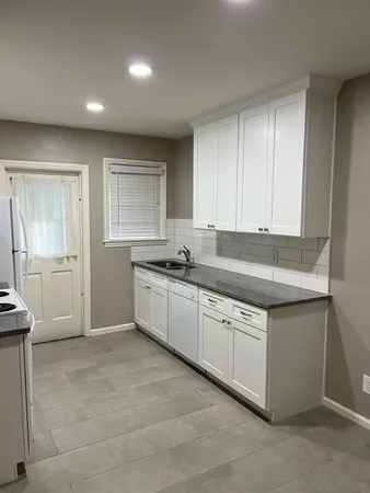 a kitchen with granite countertop white cabinets and white appliances