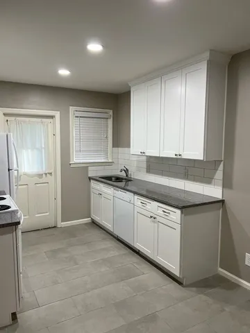 a kitchen with granite countertop white cabinets and white appliances
