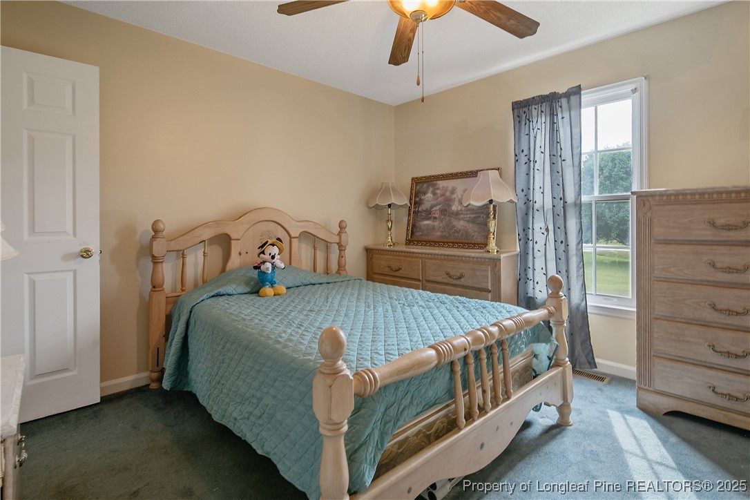 6042 Elliott Bridge Road Linden, NC 28356 - Photo 35 of 47 a bedroom with a bed next to a window and a chandelier