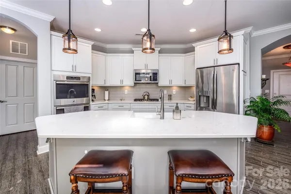 a kitchen with stainless steel appliances a table chairs refrigerator and stove