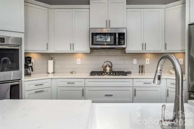 a kitchen with white cabinets and black appliances
