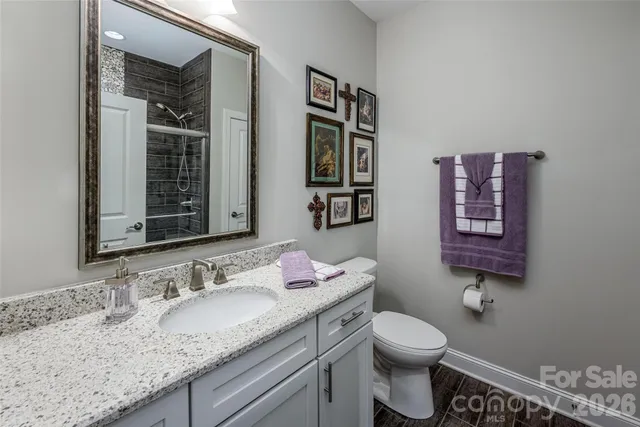 a bathroom with a granite countertop sink vanity mirror and toilet