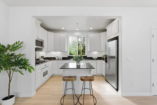 a kitchen with granite countertop white cabinets and stainless steel appliances