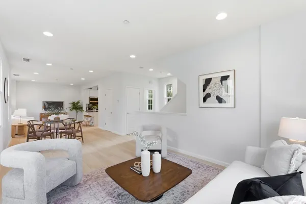 a living room with furniture and a dining table with wooden floor