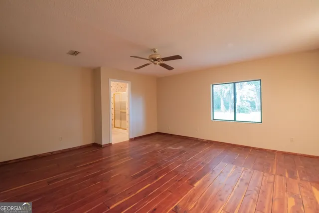 a view of an empty room with a window and wooden floor