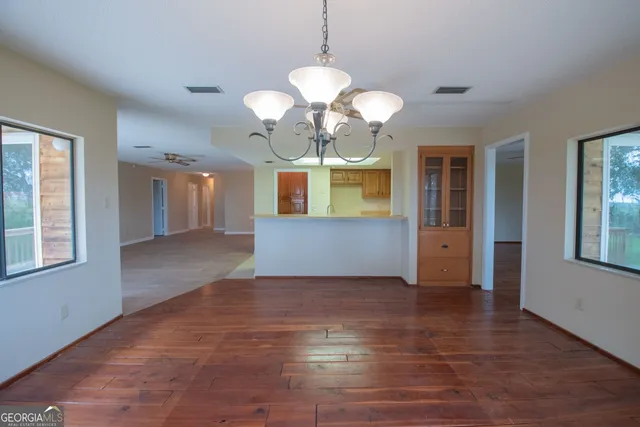 an empty room with wooden floor fan and windows