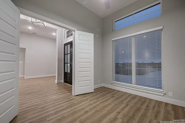 a view of an empty room with wooden floor and windows