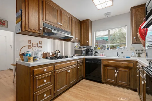 a kitchen with stainless steel appliances granite countertop a stove a refrigerator a sink a dining table and chairs with wooden floor