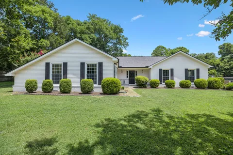 a view of a house with a big yard and potted plants
