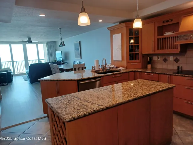 a kitchen with granite countertop a sink a counter top space and living room area