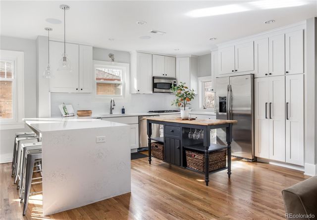 a kitchen with a refrigerator a sink dishwasher a stove and white cabinets with wooden floor