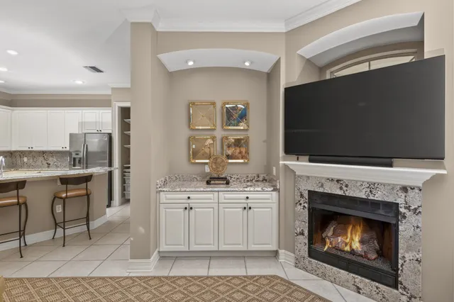 a living room with a fireplace a flat screen tv and kitchen view