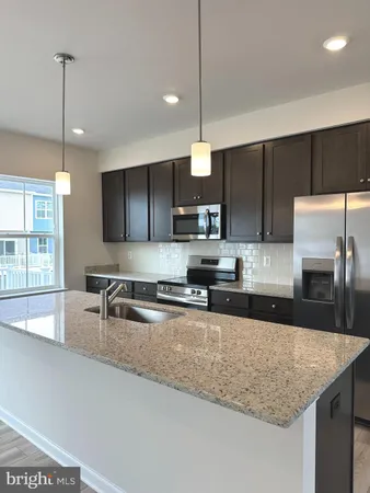 a kitchen with stainless steel appliances granite countertop a sink a stove and a wooden floors
