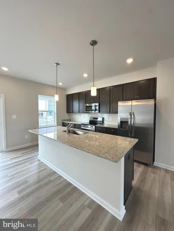 a large kitchen with kitchen island a large counter top and wooden floors
