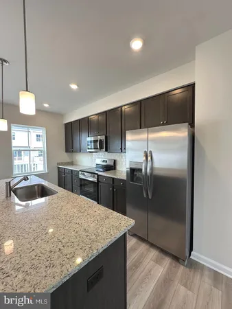 a kitchen with kitchen island a counter top space a sink stainless steel appliances and cabinets